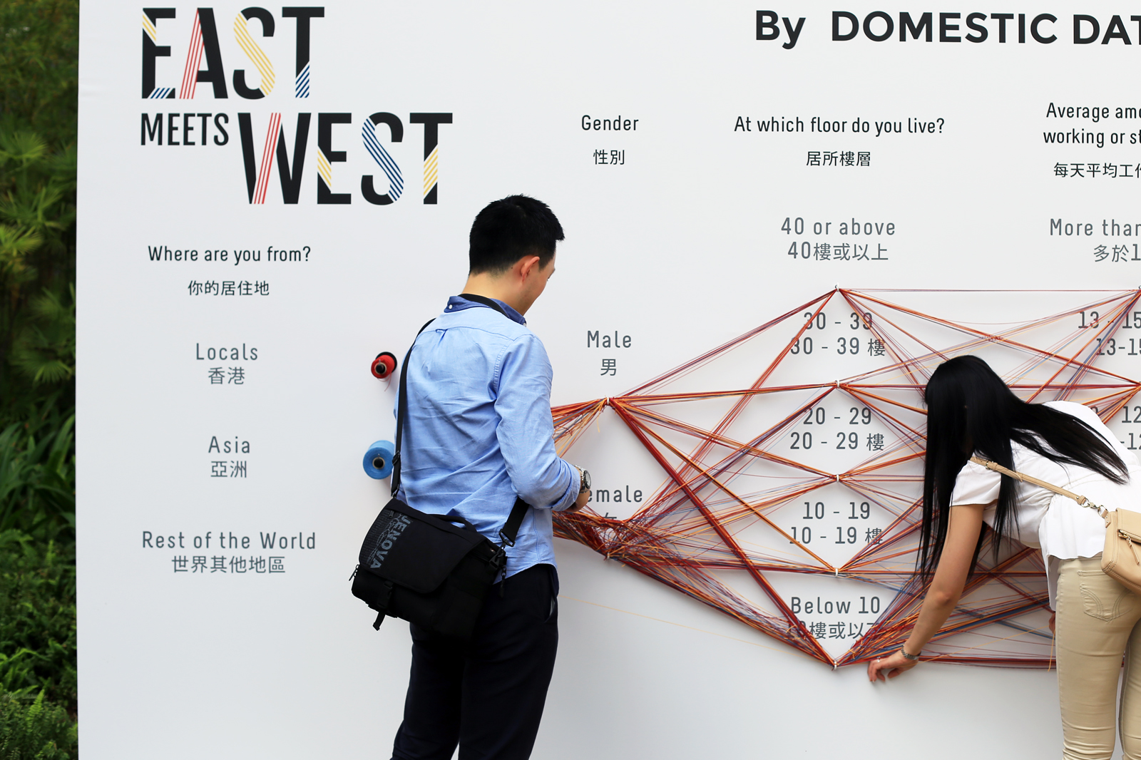 A couple interacting with a Data Strings installation called East meets West
